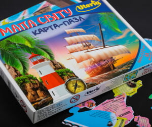 Карта - пазл. Упаковка. Для виготовлення головоломки з картону ми ретельно підібрали клей для двобічного каширування, а лайнери з обох боків були з однакового матеріалу, ламіновані матовою плівкою. Якісна висічка пазлів та їх подальша контрольована збірка в упаковку з мікрогофрокартону створили хороший і справді якісний виріб